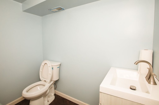 bathroom with visible vents, toilet, wood finished floors, baseboards, and vanity