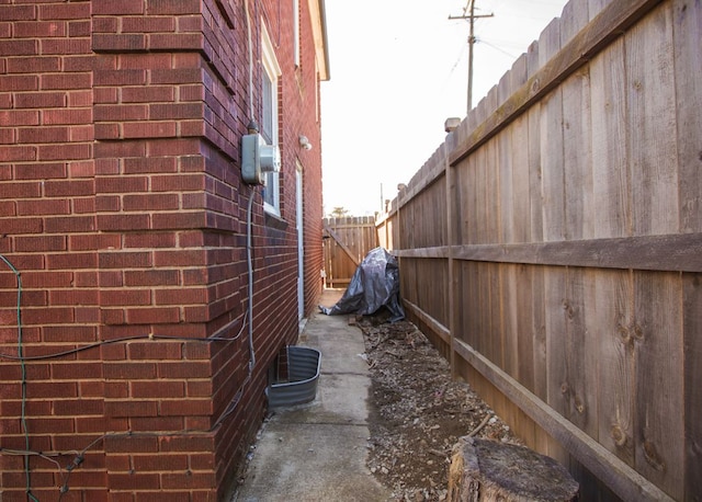 view of side of property featuring brick siding and fence