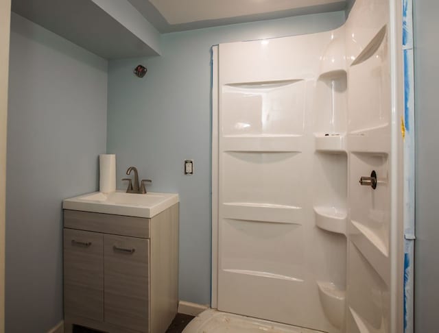 bathroom with vanity, a shower, and baseboards