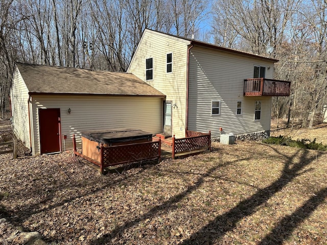 back of house with central AC unit and a hot tub