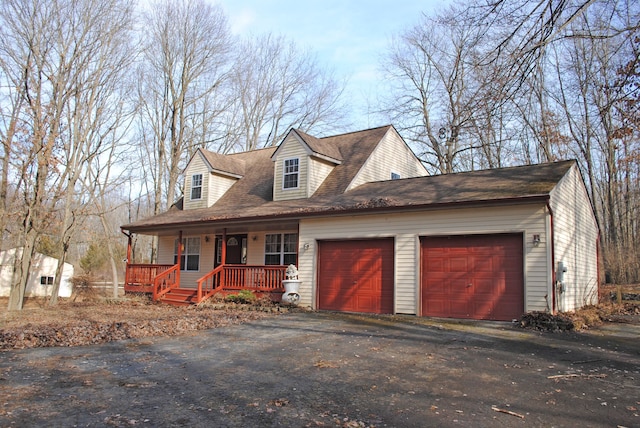 cape cod house featuring aphalt driveway, an attached garage, a porch, and a shingled roof