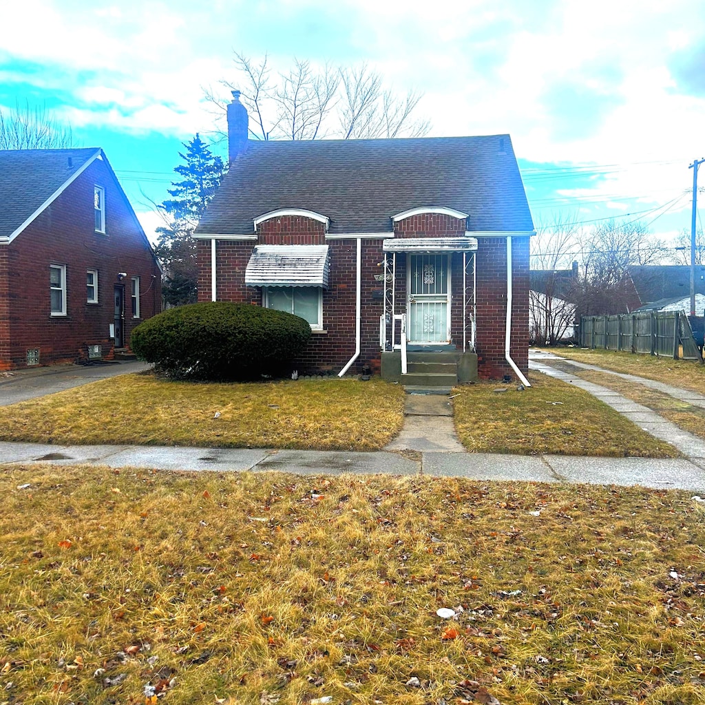 bungalow-style house with fence, a shingled roof, a chimney, a front lawn, and brick siding