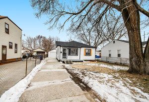 bungalow-style home with a detached garage, an outdoor structure, and fence