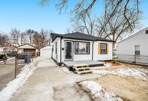 rear view of property with a detached garage, an outdoor structure, and fence