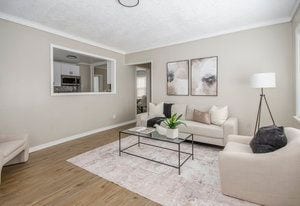 living room with crown molding, wood finished floors, and baseboards