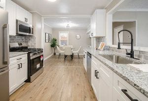 kitchen with light wood-style flooring, a sink, backsplash, appliances with stainless steel finishes, and white cabinets