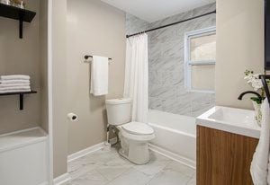 full bath featuring vanity, toilet, marble finish floor, and shower / tub combo