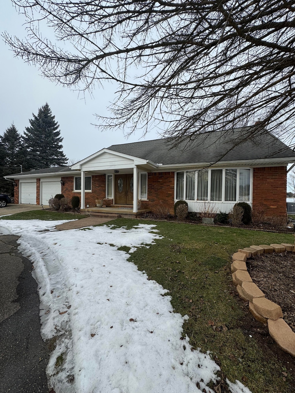 ranch-style house featuring a garage, brick siding, and a front yard