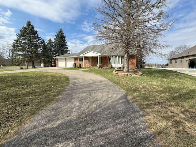 view of front of house with a front lawn, a garage, brick siding, and aphalt driveway