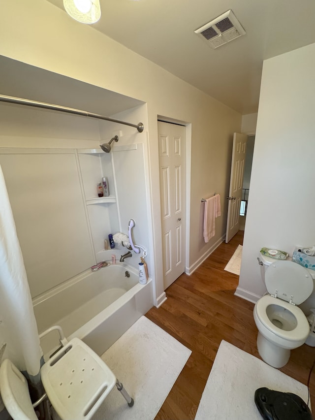 full bathroom with toilet, baseboards, visible vents, shower / tub combination, and wood finished floors