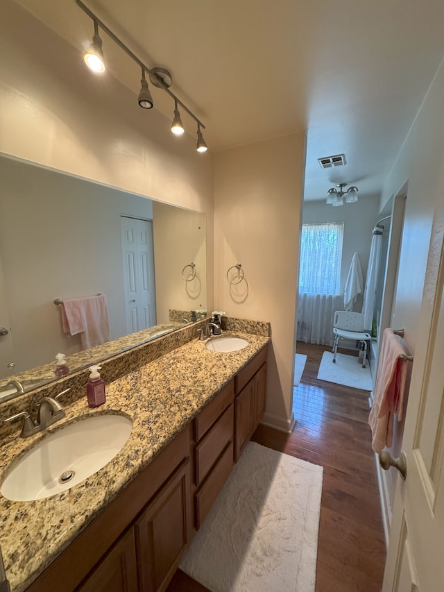 bathroom with double vanity, a sink, wood finished floors, and visible vents