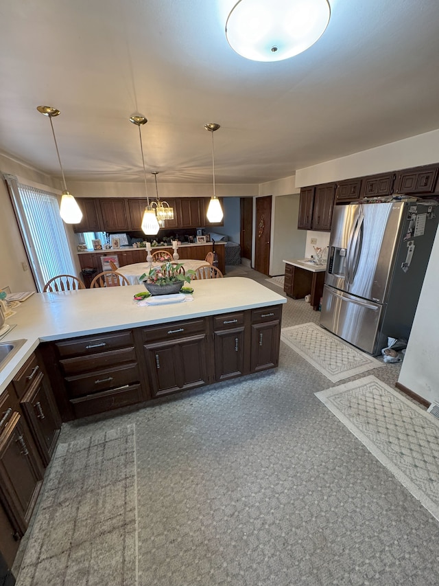 kitchen with light countertops, pendant lighting, stainless steel refrigerator with ice dispenser, and dark brown cabinets