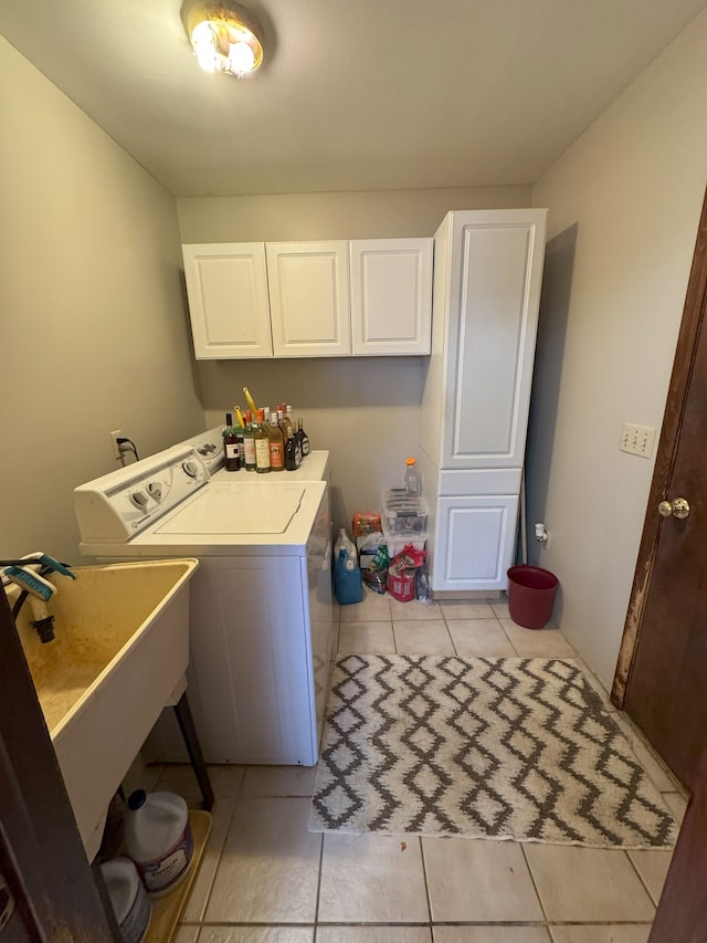 laundry area featuring washing machine and dryer, cabinet space, and light tile patterned floors