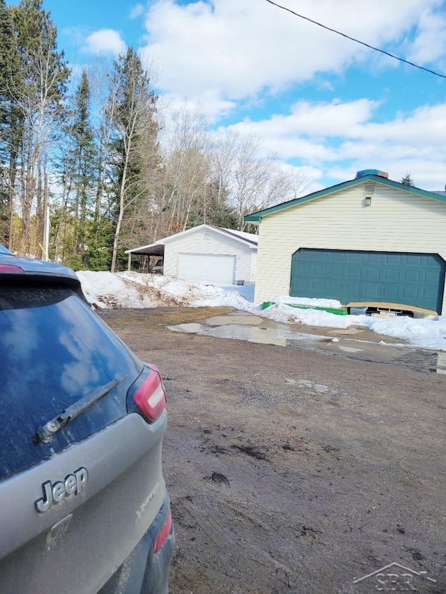 view of side of home featuring a detached garage and an outbuilding