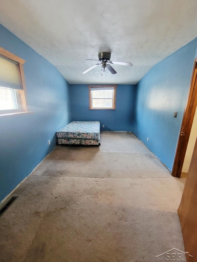 unfurnished bedroom with carpet flooring, a textured ceiling, and a ceiling fan