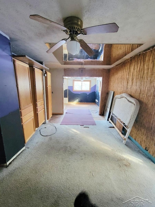 interior space featuring carpet floors, a textured ceiling, wood walls, and a ceiling fan