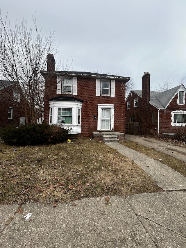 view of front facade with brick siding and a chimney