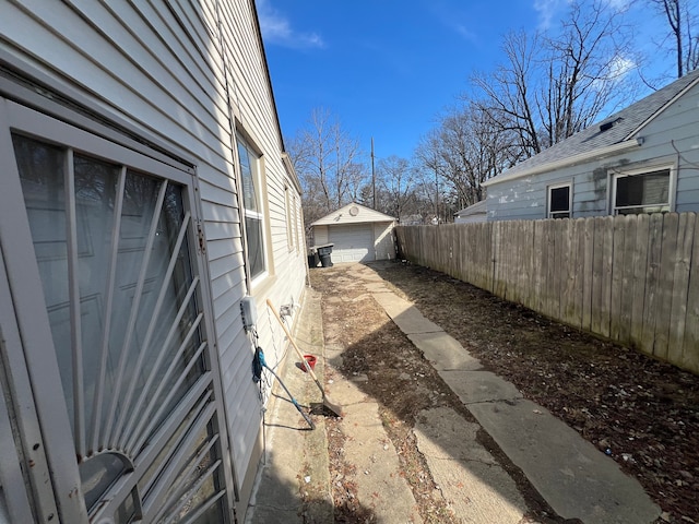 view of yard featuring an outbuilding, a detached garage, fence, and driveway