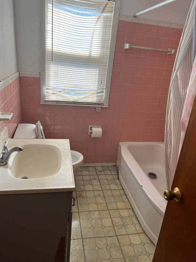 full bathroom with tile walls, a wainscoted wall, toilet, shower / bathing tub combination, and vanity