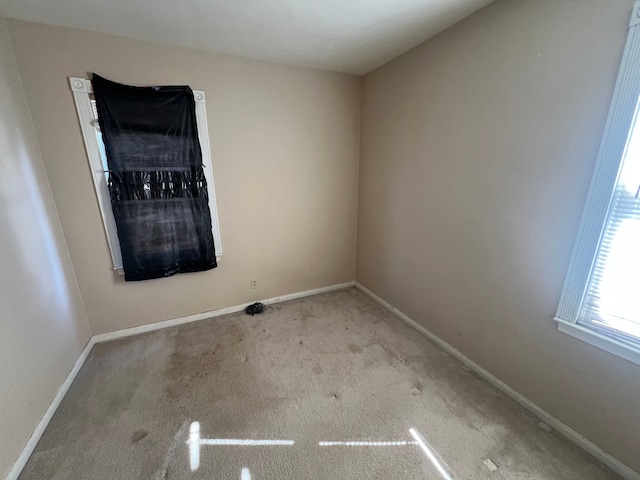 carpeted spare room featuring baseboards