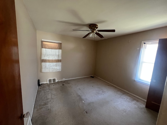 carpeted empty room featuring a ceiling fan, baseboards, and visible vents