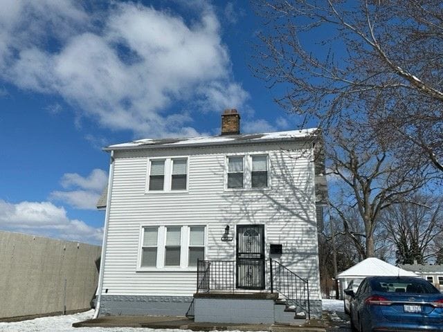 view of front facade with a chimney and fence