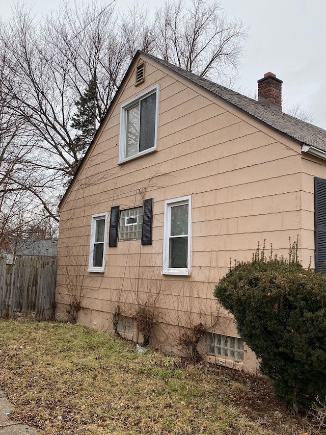 view of side of home with a chimney and fence