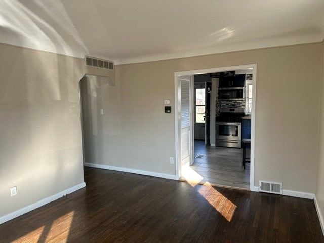 unfurnished room with wood finished floors, visible vents, and baseboards