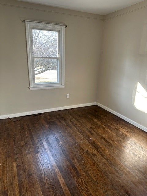 empty room featuring dark wood finished floors and baseboards