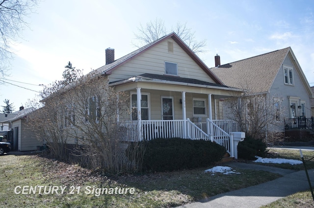 bungalow-style house featuring covered porch, a chimney, and a shingled roof