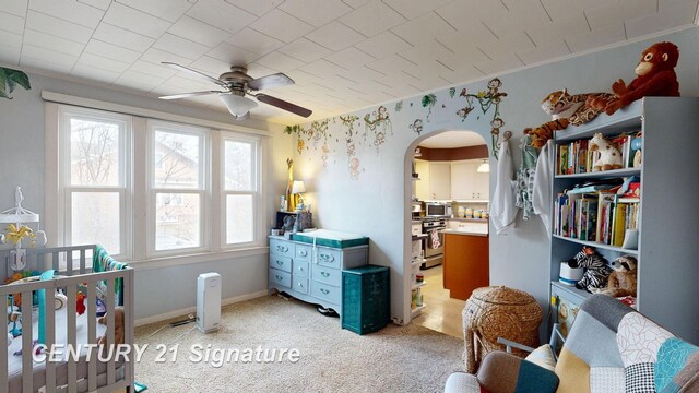 bedroom with baseboards, arched walkways, and light carpet