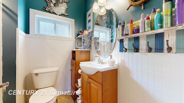 half bathroom with tile patterned floors, toilet, and vanity