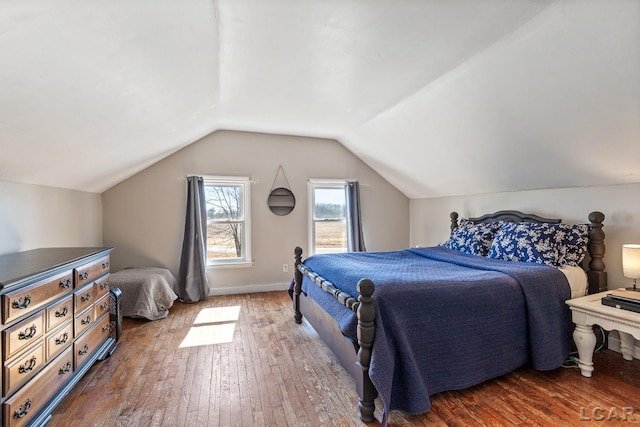 bedroom featuring baseboards, vaulted ceiling, and hardwood / wood-style flooring