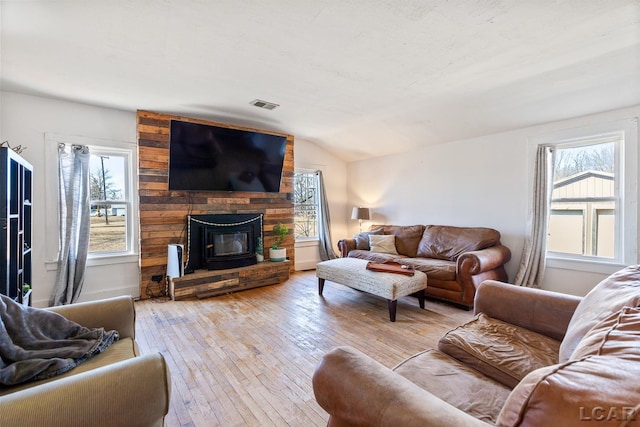 living area with vaulted ceiling, light wood-style flooring, plenty of natural light, and visible vents