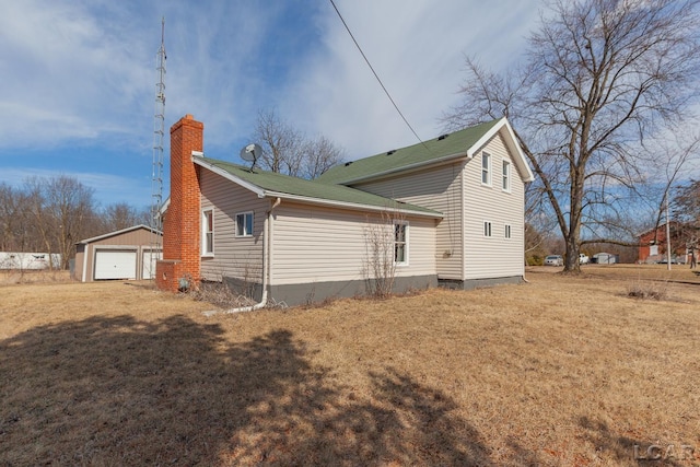 view of property exterior featuring an outbuilding, a garage, a chimney, and a yard