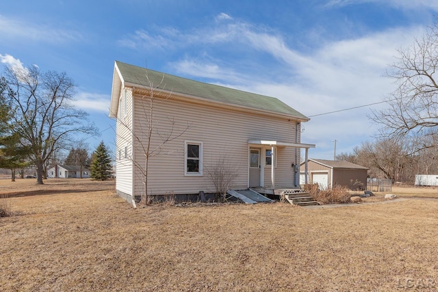 rear view of property with an outdoor structure, a yard, and a garage