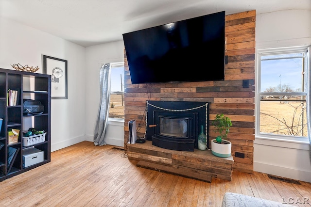 living room featuring visible vents, baseboards, hardwood / wood-style floors, and a wood stove