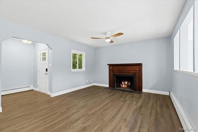 unfurnished living room with baseboards, baseboard heating, wood finished floors, a ceiling fan, and a baseboard radiator