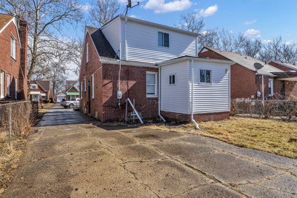 exterior space with brick siding, concrete driveway, and fence