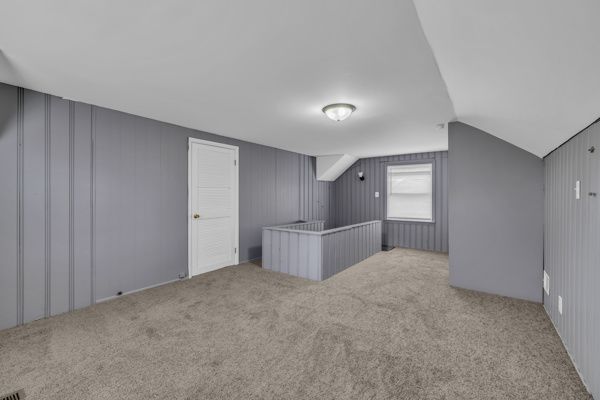 additional living space with carpet floors and vaulted ceiling