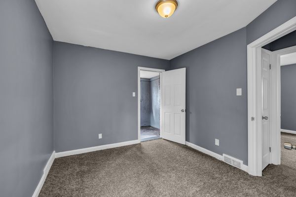 unfurnished bedroom featuring baseboards, carpet floors, and visible vents