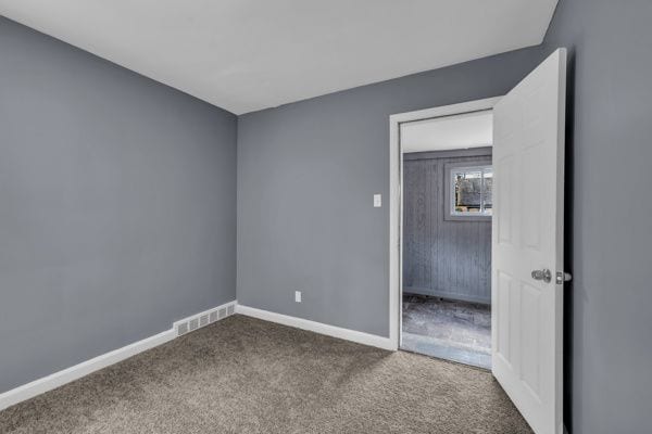 unfurnished bedroom with baseboards, carpet floors, and visible vents