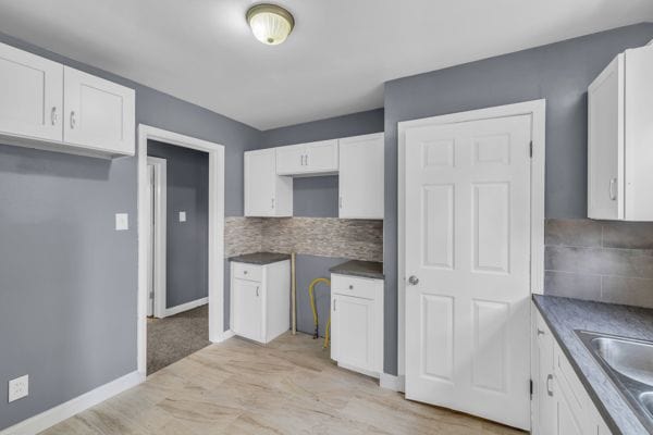 kitchen with baseboards, tasteful backsplash, and white cabinets