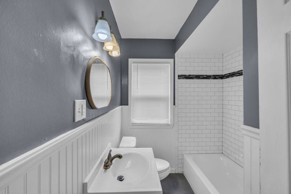 full bathroom with a wainscoted wall, toilet, vanity, and bathing tub / shower combination