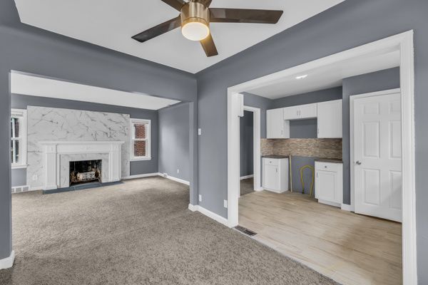 unfurnished living room featuring a premium fireplace, baseboards, carpet, and visible vents