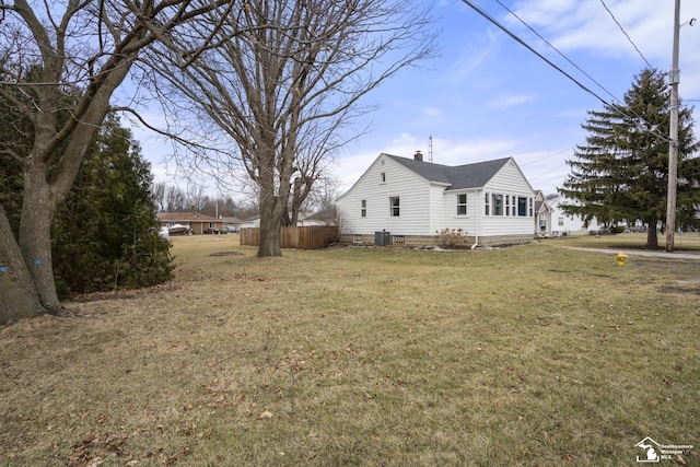 view of side of property with a yard, fence, cooling unit, and a chimney