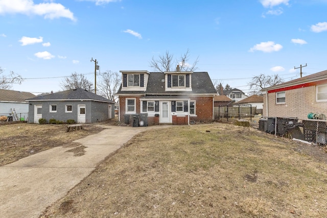 view of front of property with brick siding, a chimney, a front yard, and fence