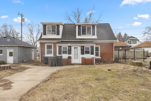 view of front facade with a front lawn, fence, roof with shingles, brick siding, and a chimney