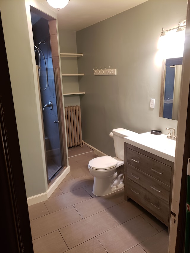 bathroom featuring vanity, radiator, a stall shower, tile patterned flooring, and toilet