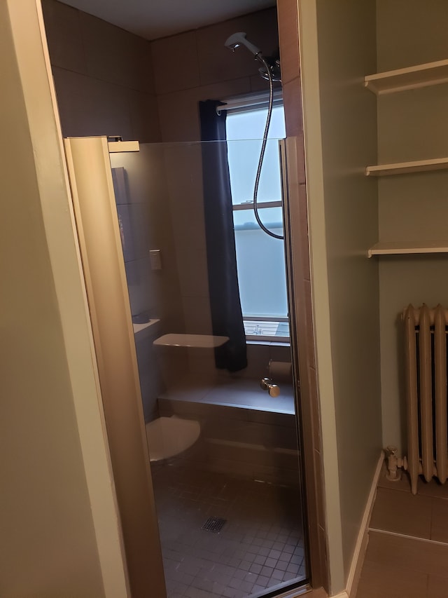 full bath with baseboards, radiator, a stall shower, and tile patterned flooring